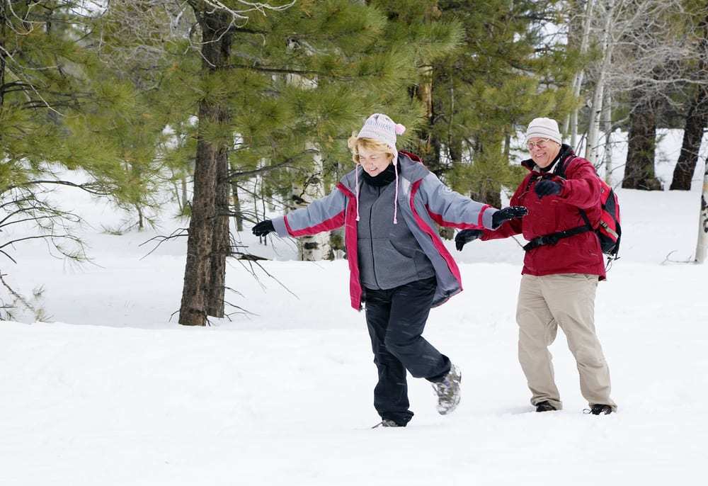 Active-retired-couple-walking-in-the-snow-smiling