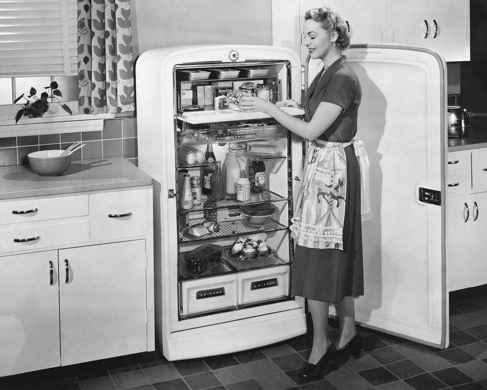 Black-and-white-photo-of-woman-taking-things-out-of-her-fridge-in-the-1950s