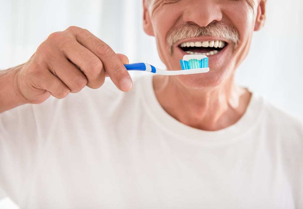 Close-up-of-senior-man-about-to-brush-his-teeth-smiling