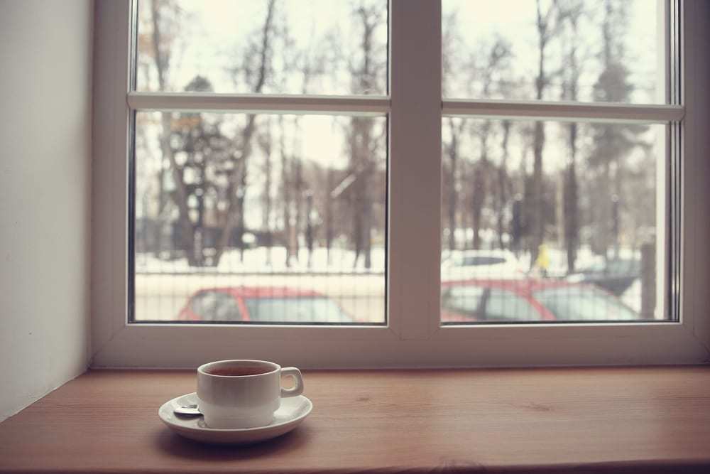Cup-of-tea-on-window-ledge-winter-scene-outside-with-bare-trees-and-parked-cars