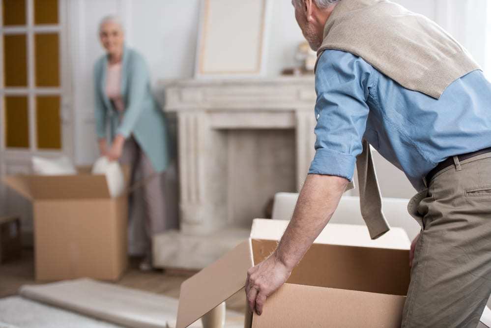 senior couple packing up house in cardboard boxes