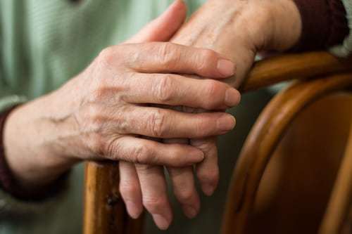 two hands of an elderly woman sitting on the back of a chair