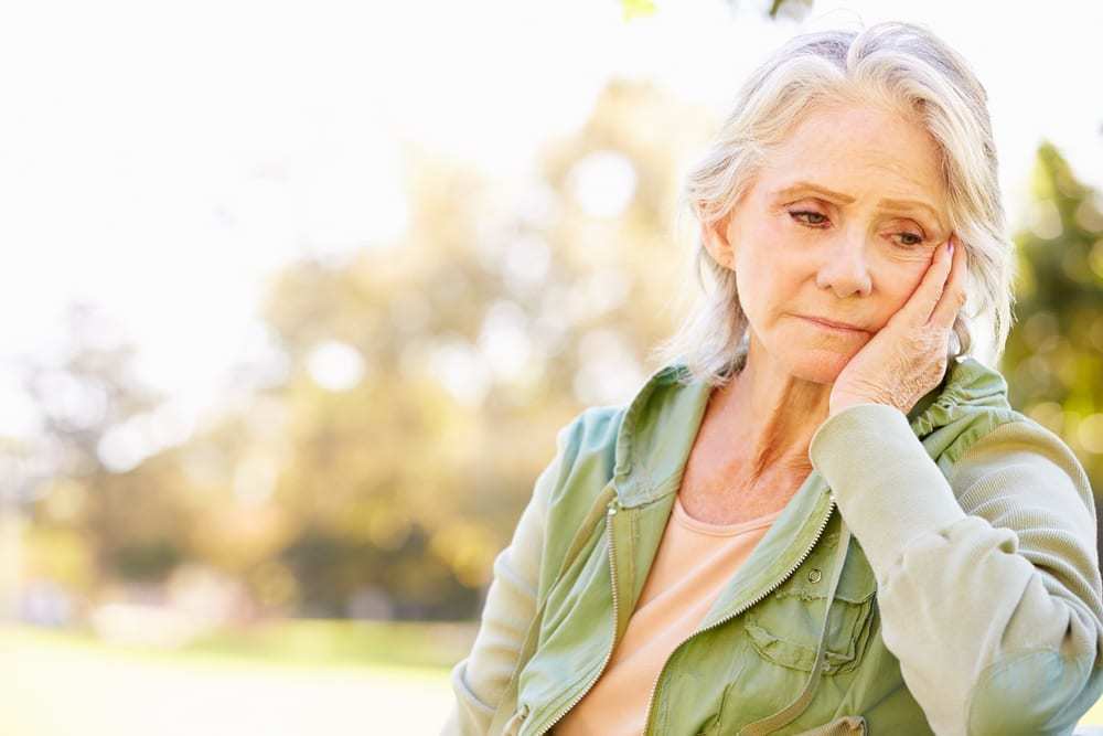 Senior woman with sad expression sitting outside