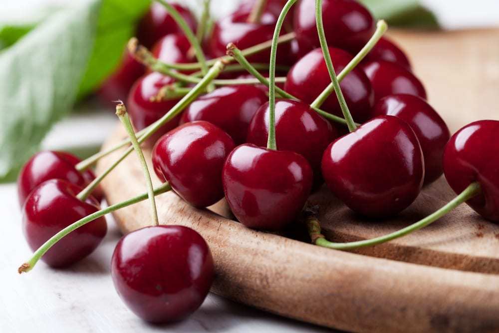 Fresh-cherries-on-a-wood-serving-plate-on-countertop