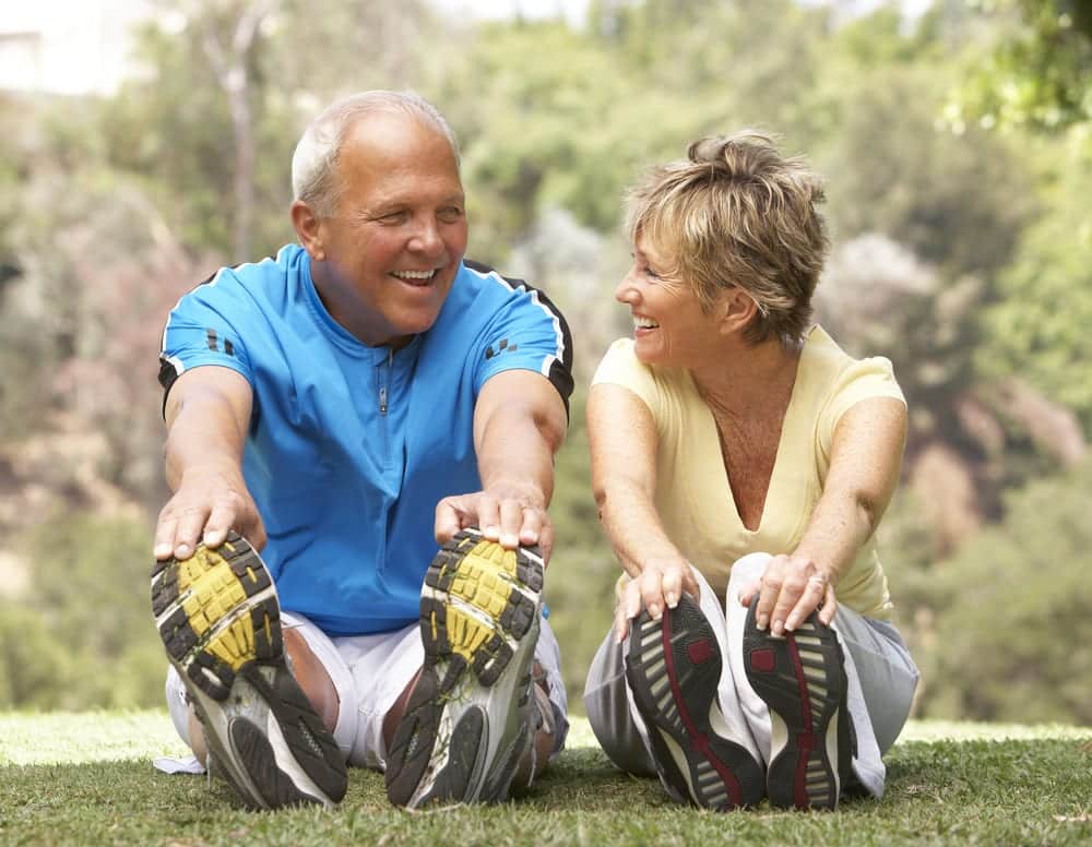 Senior-couple-smiling-and-stretching-in-the-park