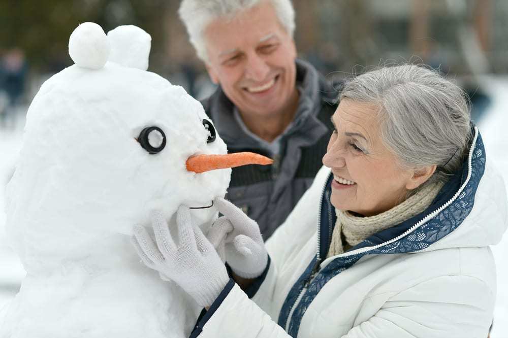 Smiling-senior-couple-building-a-snowman