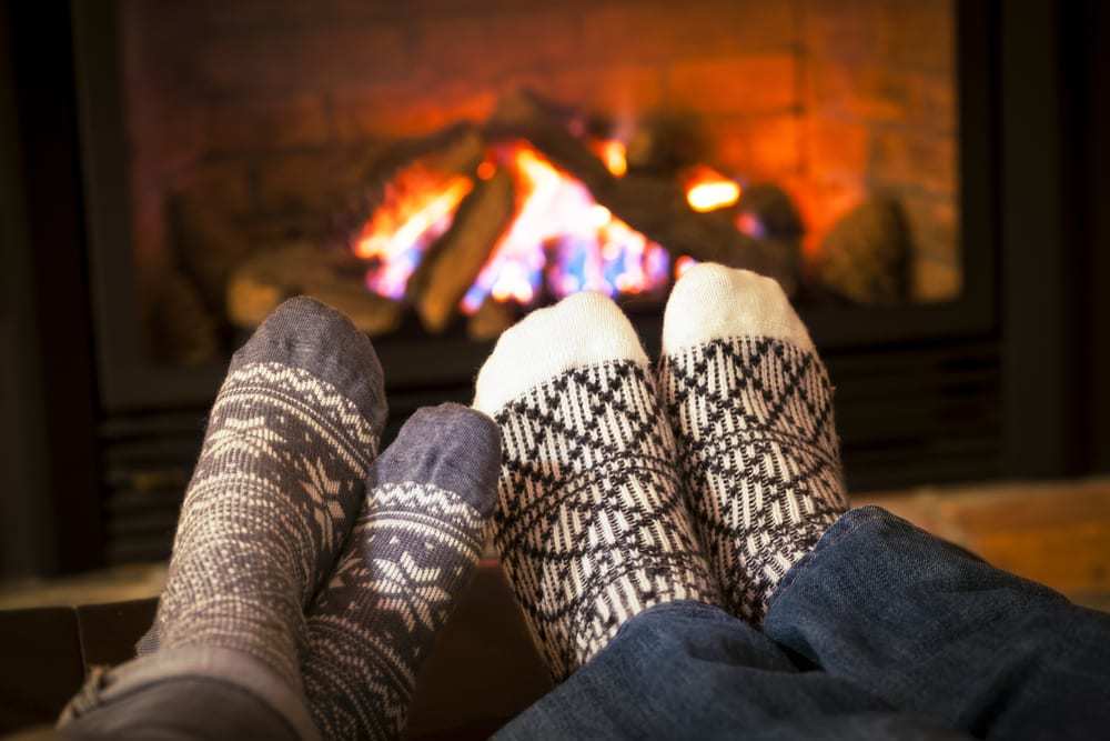 Two-feet-in-festive-winter-socks-in-front-of-a-fireplace-with-a-burning-fire