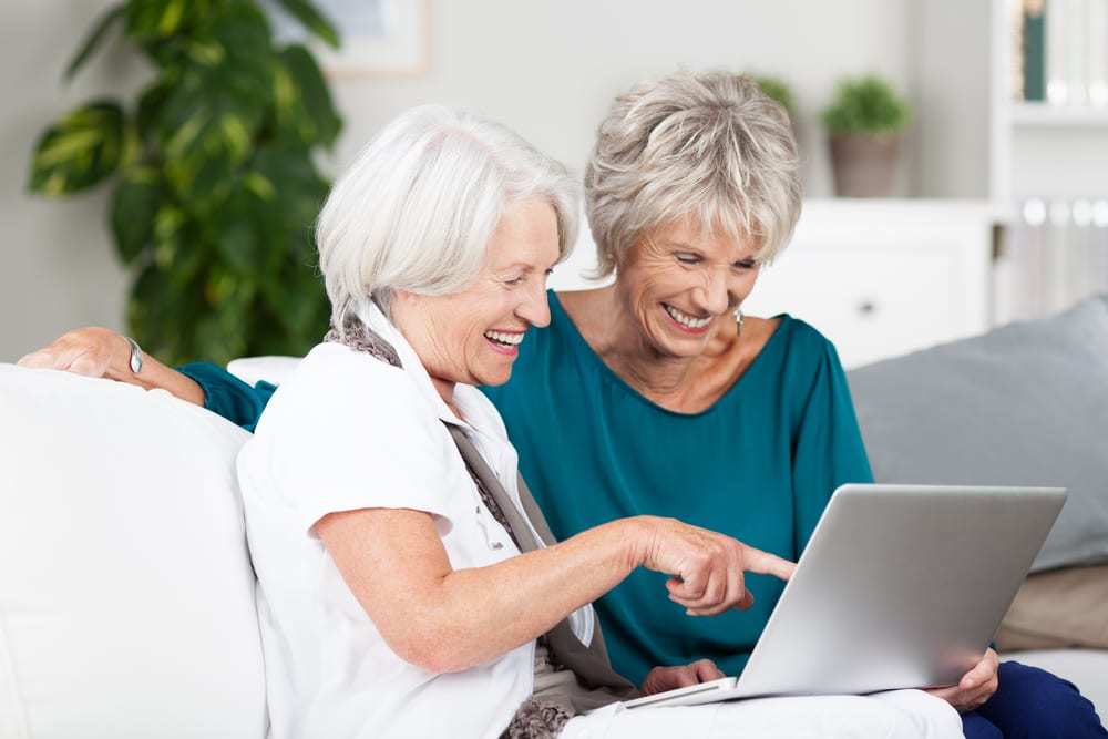 Two-senior-women-looking-at-laptop-laughing