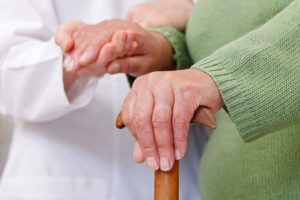 nurse and old woman hold hands