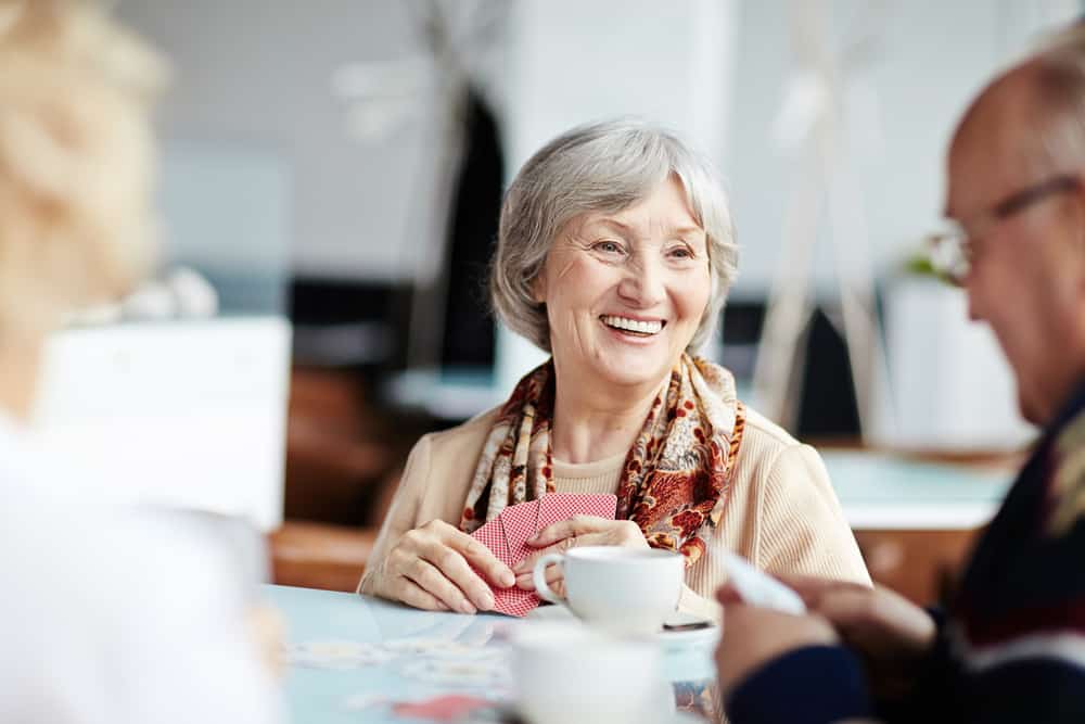 senior woman smiling while playing cards with friends