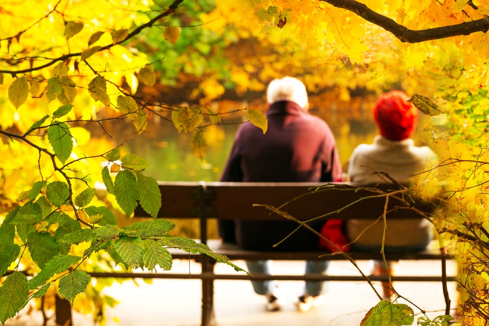 Senior couple sitting on bench in fall
