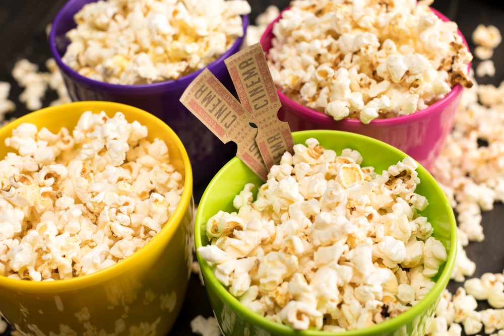 Four bowls filled with popcorn, cinema tickets