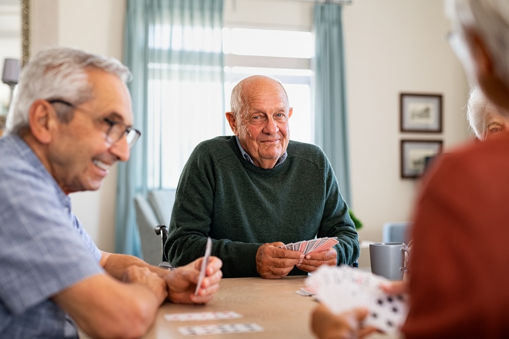 Smiling senior man playing cards with friends