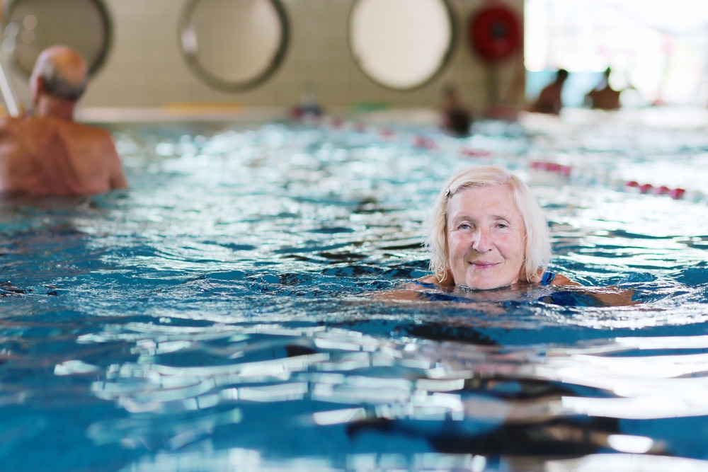 Smiling senior woman swimming in indoor pool