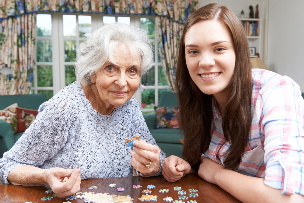 Senior woman and young woman smiling and doing a puzzle together