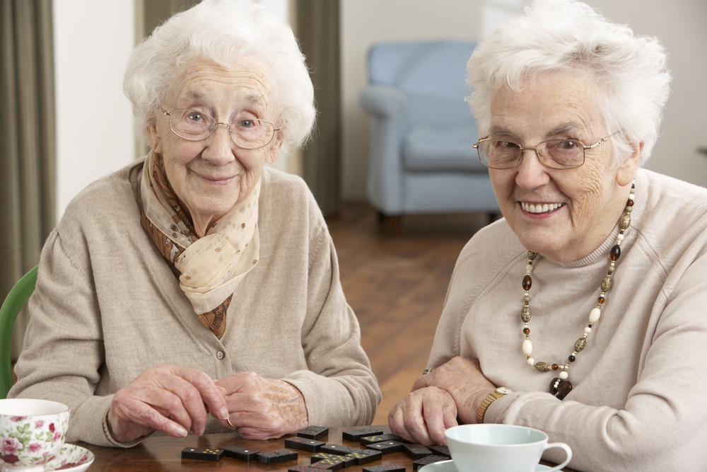 Two senior women playing dominoes, smiling