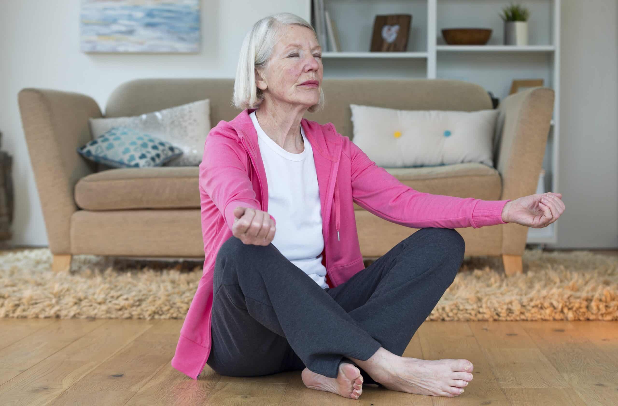 Senior woman sitting on floor, meditating at home