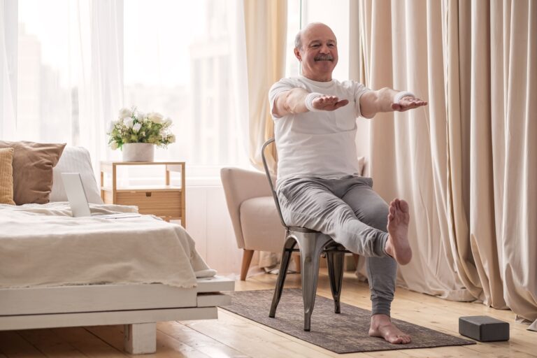Senior man sitting in chair lifting on leg and both arms to exercise