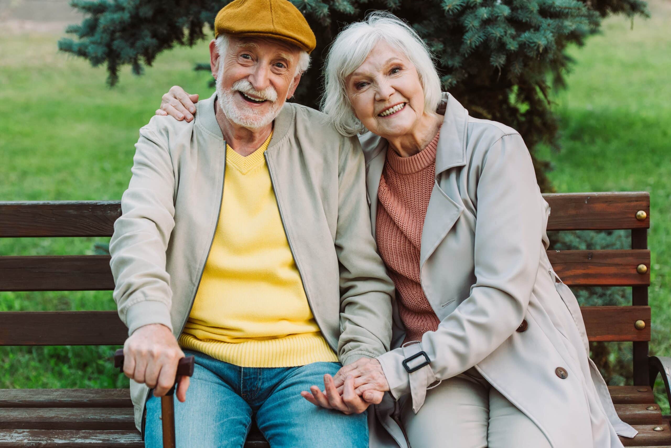 Smiling senior couple holding hands on park bench