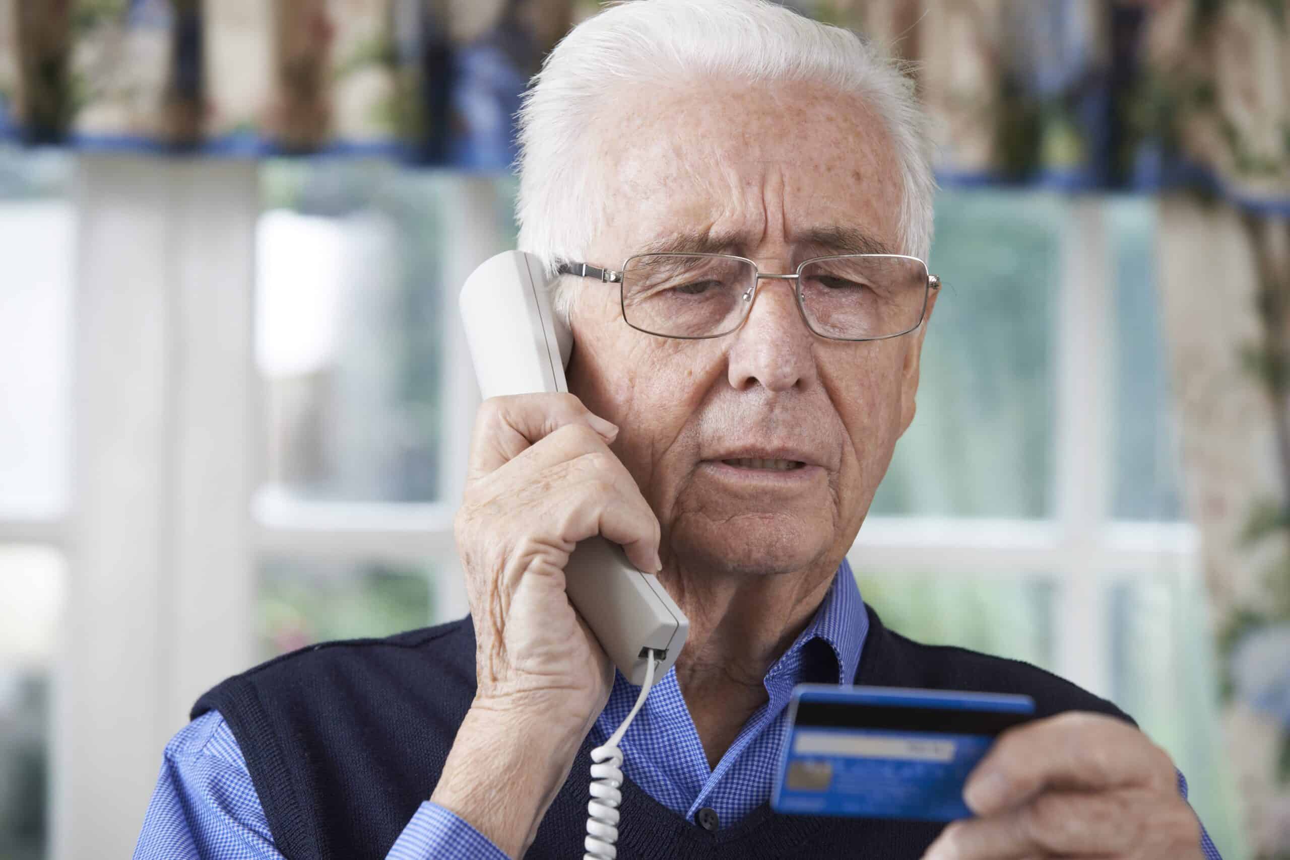 Concerned senior man talking on phone and holding credit card