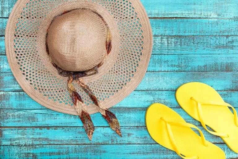 Sun hat and yellow flip flops on wood painted turquoise