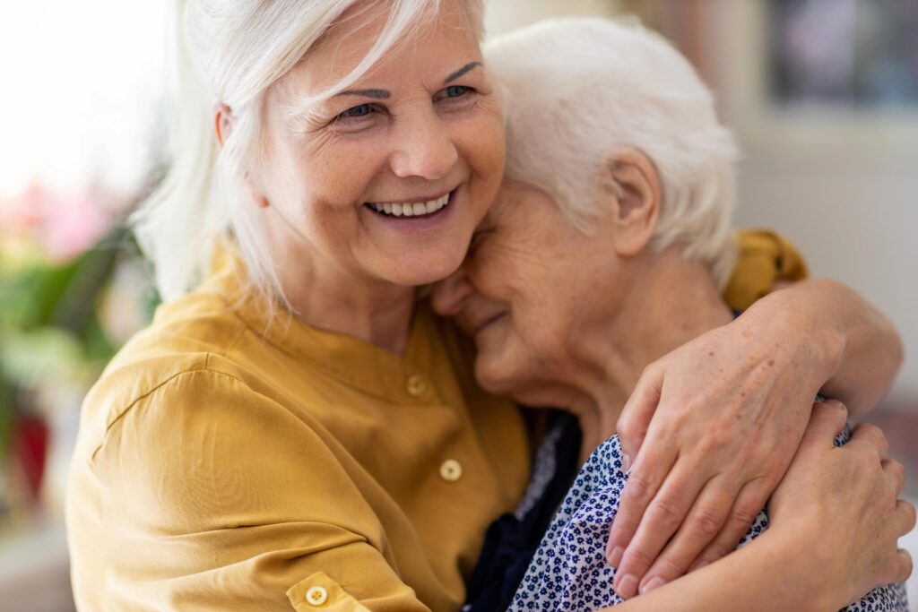 two senior women smiling and hugging