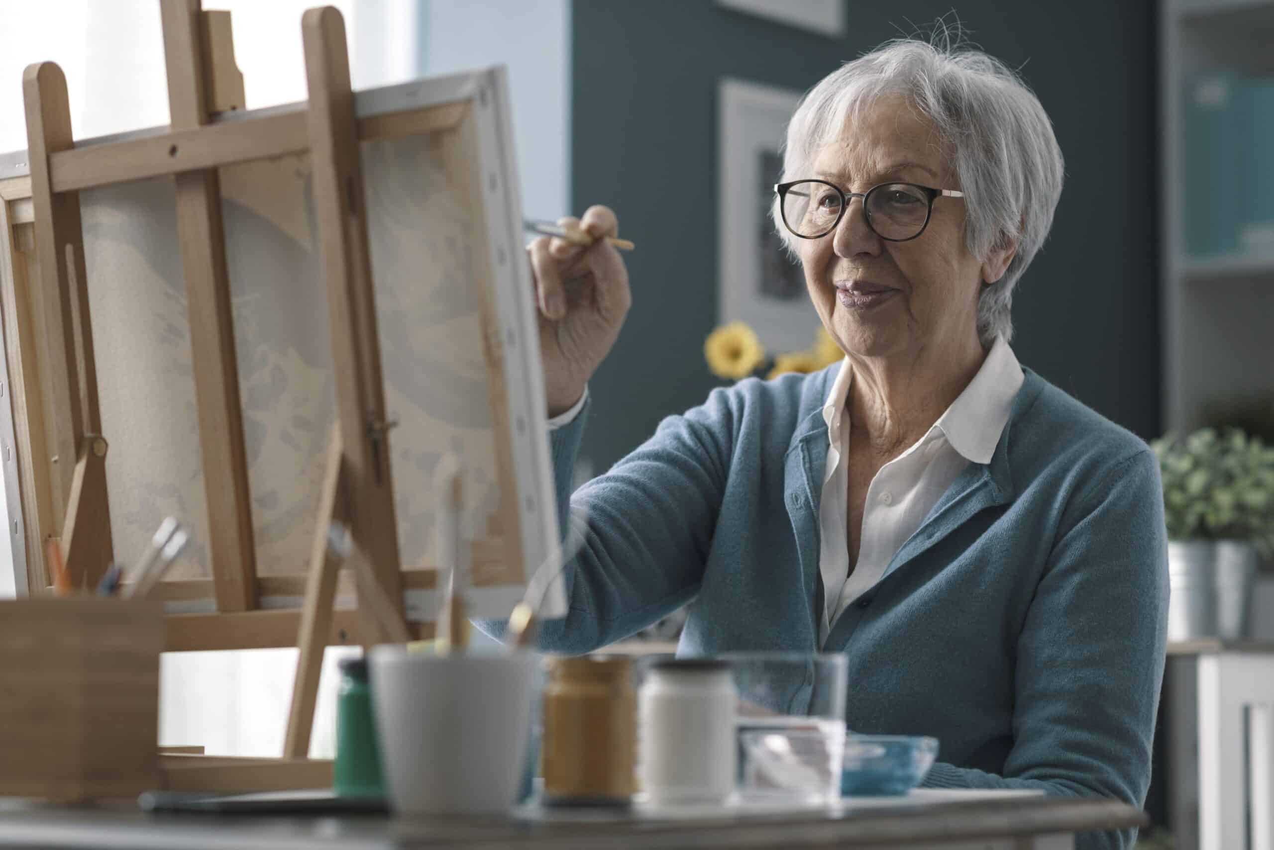 senior woman painting on easel