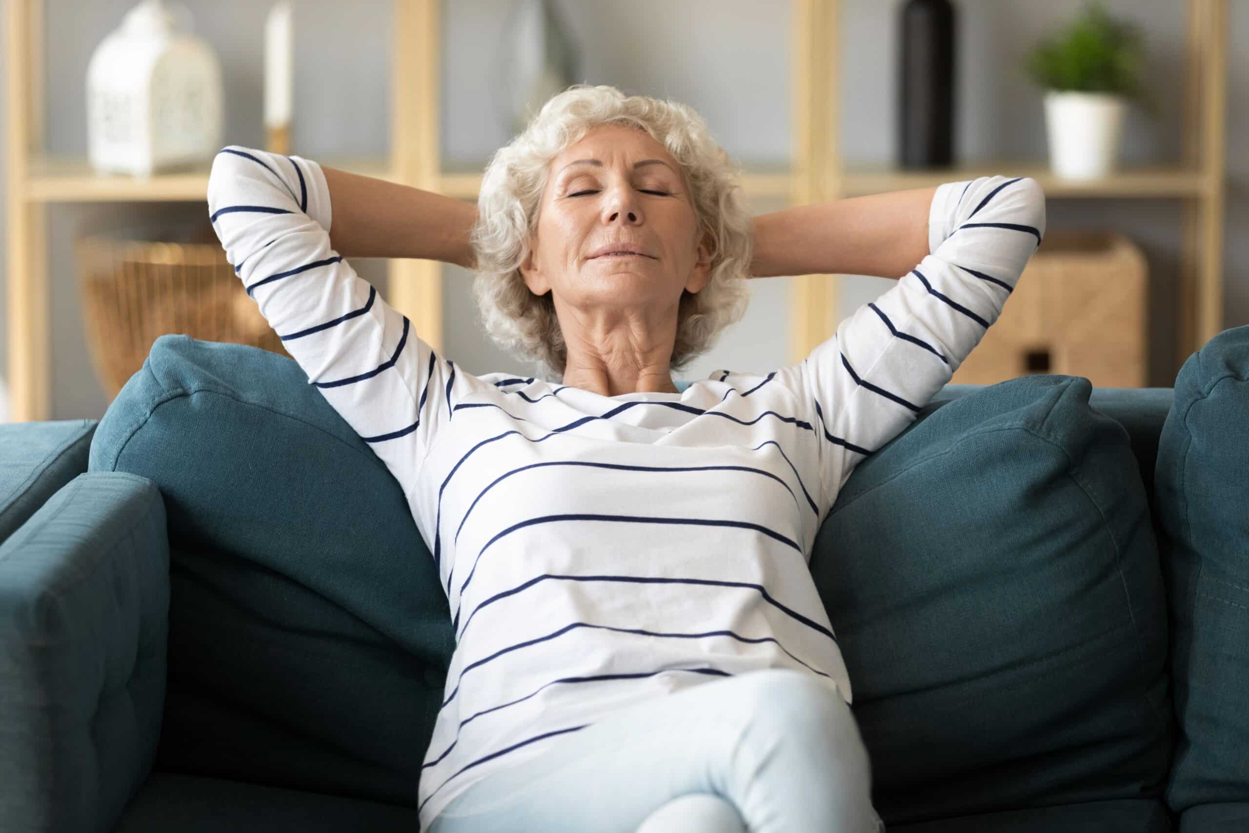 Senior woman relaxing on couch with eyes closed